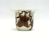 un vase blanc orné d'un motif floral marron