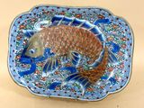 une assiette bleue et orange sur laquelle est représenté un poisson