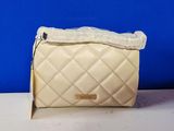 beige quilted purse with a white bow on top of it
