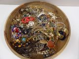 a wooden bowl filled with lots of jewelry on a table