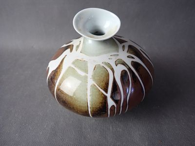 a brown and white vase sitting on a table