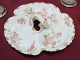 une assiette blanche ornée de fleurs roses, posée sur une table rouge