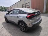 the rear end of a silver car parked in front of a building