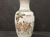 a white vase with a painting on it sitting on a table
