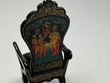 a miniature chair with a painting on the back of it