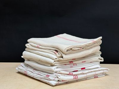 une pile de cinq nappes blanches et rouges posée sur une table en bois