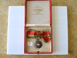 une boîte rouge contenant une médaille en argent et un ruban rouge
