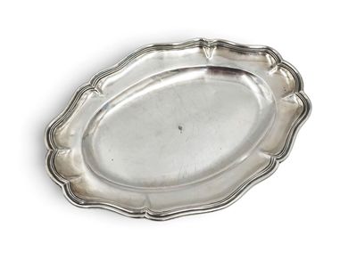 an oval silver plate with a scalloped edge on a white surface