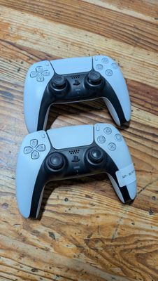 deux manettes de jeux vidéo posées sur un parquet