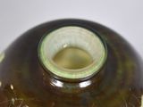 a brown and green vase sitting on a white table