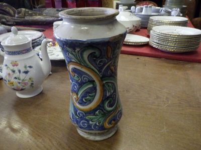 un vase posé sur une table, avec des assiettes et des tasses en arrière-plan