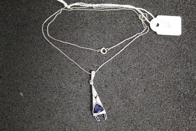 un collier en argent auquel est suspendue une pierre bleue