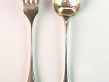 two spoons and a fork on a white surface