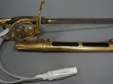 a gold colored sword with a black handle and a white cord