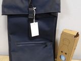 backpack with tag and cardboard box on wooden floor next to wall
