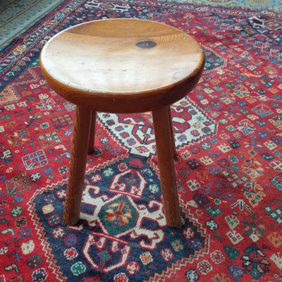 un petit tabouret en bois posé sur un tapis dans un salon