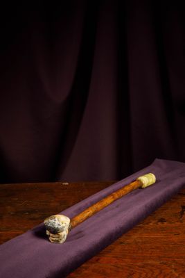 an old pipe sitting on top of a wooden table next to a purple cloth
