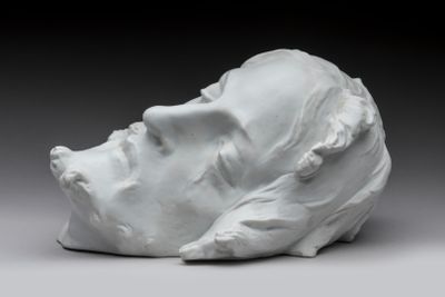 une sculpture blanche représentant la tête d'un homme posée sur une table