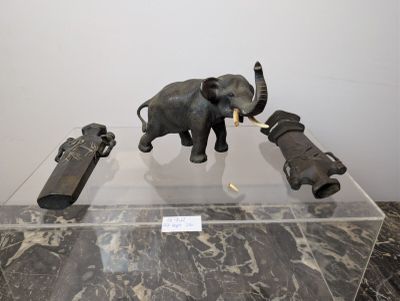 an elephant and a gun on display in a glass case