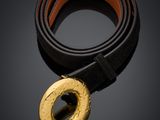 une ceinture noire et dorée avec une boucle dorée sur fond noir
