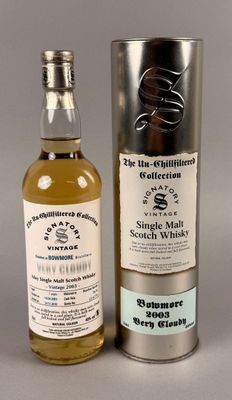 une bouteille de whisky posée à côté d'un bidon en métal