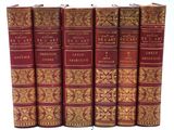 six livres rouges sont alignés sur une surface blanche
