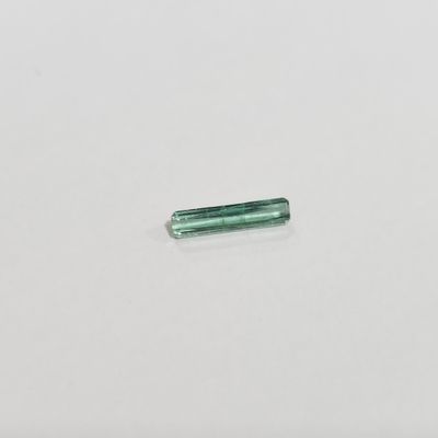 une seule tourmaline verte posée sur un fond blanc