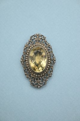 a close up of a broochle with a yellow stone in it