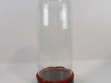 une petite cloche en verre posée sur un socle en bois, sur une surface blanche
