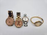 three ladies ' s wrist watches and a gold watch on a white surface