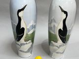 two vases with birds painted on them sitting next to a yellow ball