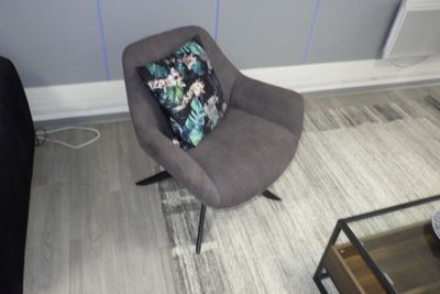un fauteuil gris avec un coussin posé dessus, dans un salon