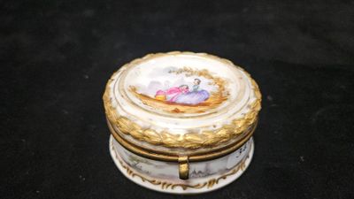 une petite boîte blanche et dorée sur laquelle figure une image