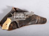 un vieux revolver posé sur un morceau de cuir, sur une surface blanche