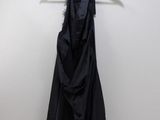a black dress hanging on a hanger against a white wall