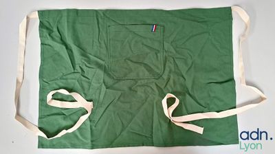 un tablier vert orné d'une bande rouge, blanche et bleue