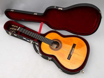 une guitare dans un étui, posée sur une surface blanche