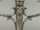 an antique silver plated candelier with three candles on it