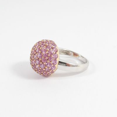 a close up of a ring with pink stones on a white surface