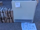 un réfrigérateur blanc posé à même le sol, à côté d'une pile de cartons