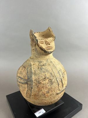 un vieux vase posé sur un socle noir, sur fond blanc