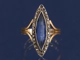 Gros plan sur une bague en or ornée d'une pierre bleue