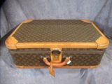 une valise marron et beige posée sur un tissu bleu