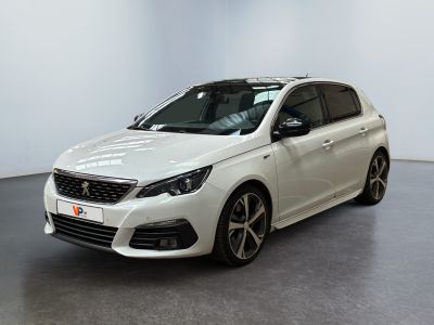 Une voiture blanche est garée dans une pièce blanche au sol noir.