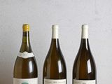trois bouteilles de vin sont alignées sur une table en bois