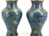 pair of blue vases with floral designs on them against a white background