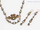 a close up of a necklace and earring set on a white surface