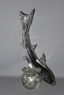 a glass sculpture of a dolphin that is on top of a glass ball