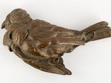 a bronze bird that is sitting on a white surface