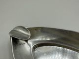 a metal urinal that is on a white wall
